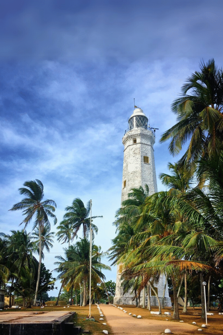 White lighthouse tower at Dondra surrounded by palm trees