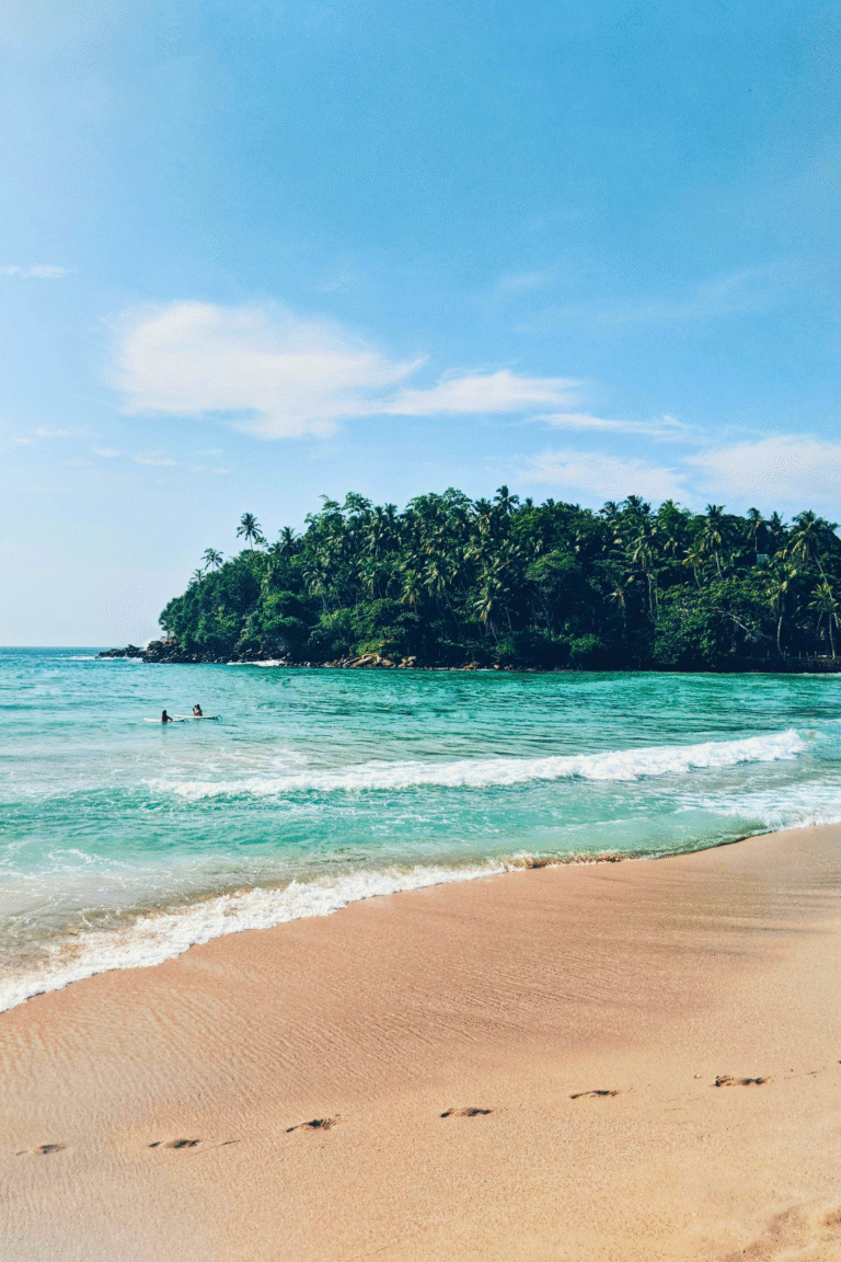 Hiriketiya Beach coastline with surfers riding waves