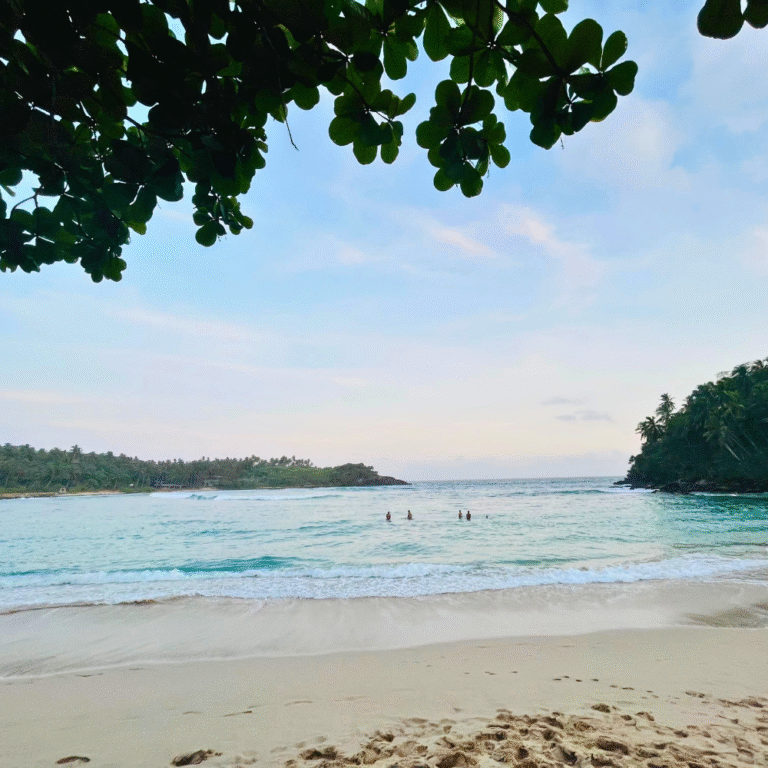 Hiriketiya Beach coastline with surfers riding waves